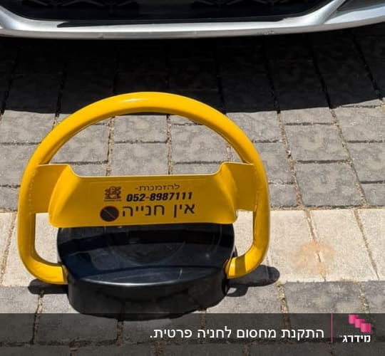 מחסום חניה פרטי צהוב מותקן על משטח אבנים משתלבות